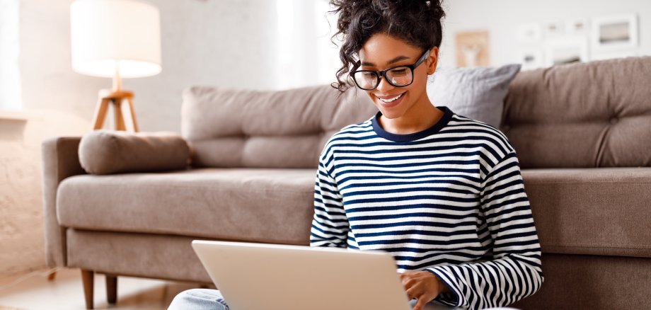 Joyful relaxed ethnic woman using laptop with interest at home